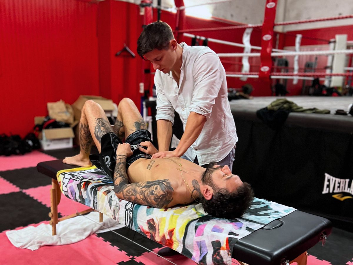 Cliquer pour agrandir Antoine Denis, ostéopathe, en séance auprès d'un sportif dans une salle de boxe
